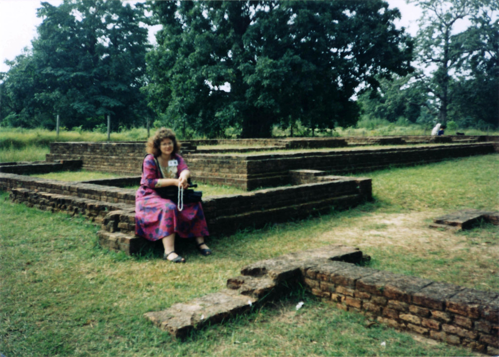 Photographer, videographer, Linda Lane taking a break with the video camera, praying using a white mala, at ruins of the